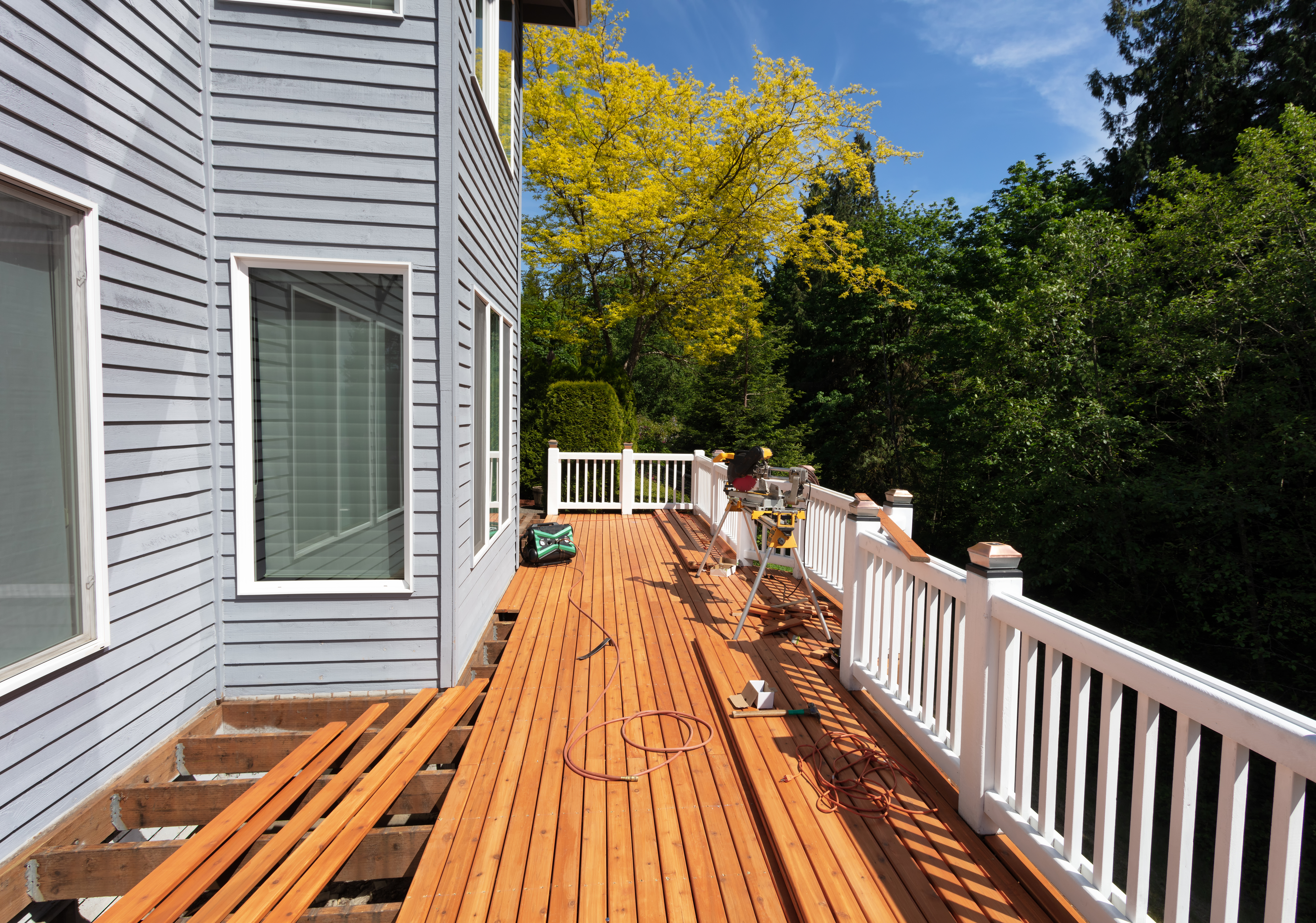 Outdoor red wooden cedar deck being remodeled with new floor boards freshly installed